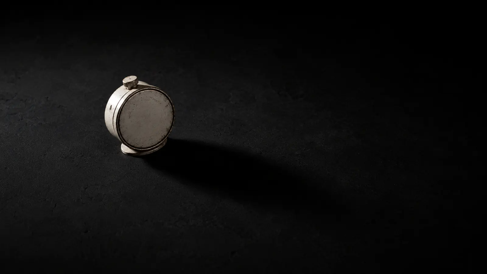 A mechanical wind-up timer alone on a bare surface