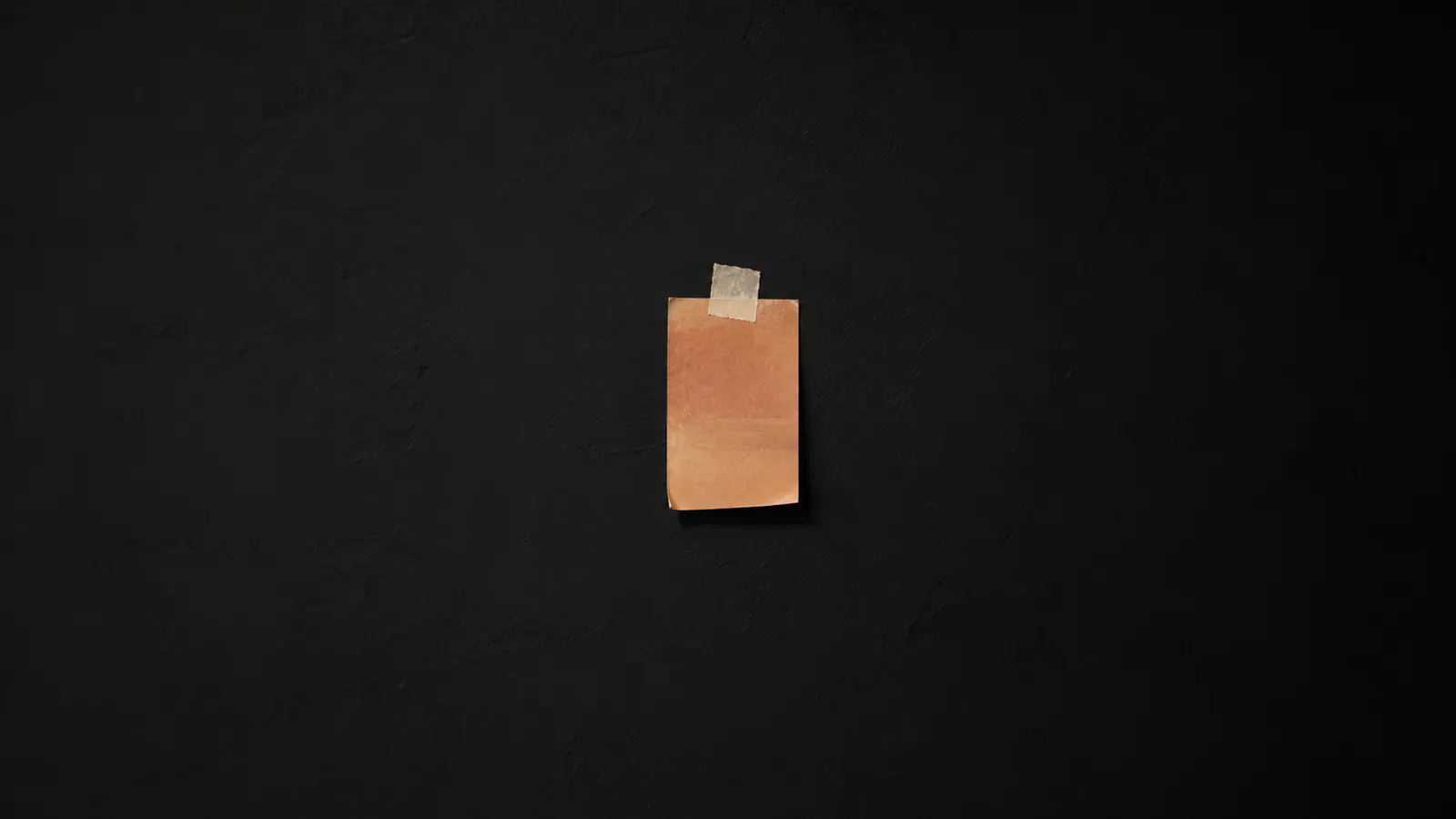A single paint swatch taped to a bare wall, edges curled